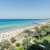 Una spiaggia con ombrelloni e lettini su sabbia dorata, mare blu e cielo limpido.