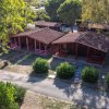 Complesso di bungalow con tetto a spiovente e portici, circondato da verde.