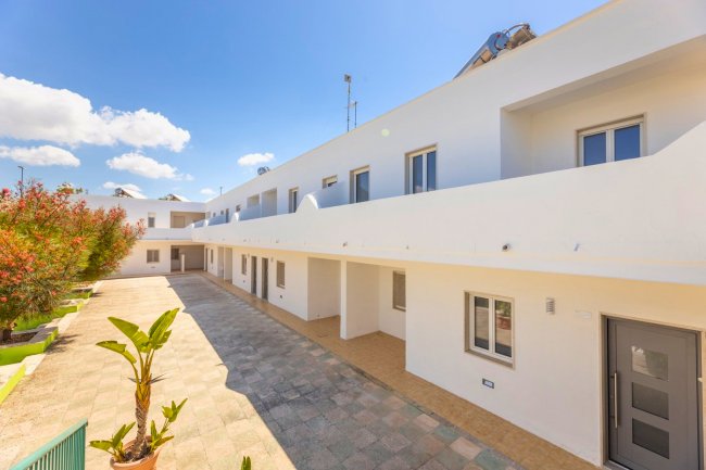 Complesso residenziale bianco con cortile e piante.