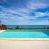 Piscina con vista mare e cielo azzurro con nuvole.