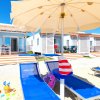 Bungalow sulla spiaggia con lettini blu e ombrellone.