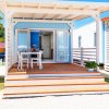 Una veranda con tavolo e sedie davanti a una casetta blu con porta aperta.