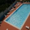 Vista dall'alto di una piscina rettangolare con lettini e ombrelloni intorno.