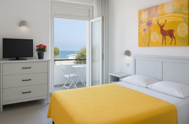 Camera da letto con letto giallo e vista mare.
