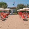 Spiaggia con lettini rossi e ombrelloni beige.