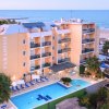 Hotel vista mare con piscina e palme verdi.