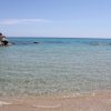 Mare trasparente con scogli e orizzonte azzurro.
