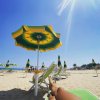 Spiaggia con ombrelloni giallo-verdi sotto un cielo azzurro.