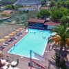 Vista aerea di una piscina rettangolare con lettini e ombrelloni colorati.