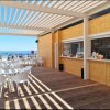 Terrazza vista mare con sedie e tavoli bianchi.