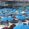 Ombrelloni blu su una spiaggia sabbiosa con edifici sullo sfondo.