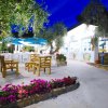 Giardino notturno con fiori, sedie in legno e ombrelloni blu.
