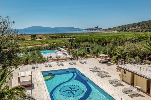 Piscina con lettini, vista su un paesaggio collinare e il mare in lontananza.
