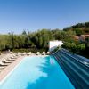 Piscina con sdraio disposte lungo i lati e vegetazione circostante.