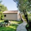 Casa con tetto di tegole rosse, sentiero curvo in cemento, alberi e prato verde.