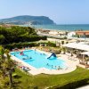Piscina all'aperto con persone, vicino alla spiaggia e vista montagna.