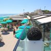 Una terrazza sul mare con ombrelloni verdi e tavolini all'aperto.