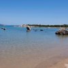 Spiaggia sabbiosa con mare calmo e rocce.