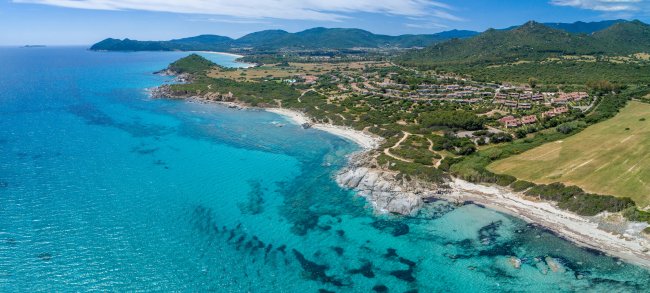Costa con mare turchese e colline verdi.