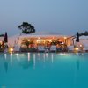 Piscina tranquilla al tramonto con sedie a sdraio e un edificio illuminato sullo sfondo.