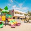 Area giochi colorata in spiaggia davanti a un edificio moderno, cielo sereno.