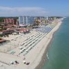 Spiaggia con ombrelloni colorati, mare limpido e edifici sullo sfondo.