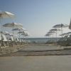 Ombrelloni e lettini bianchi su una spiaggia sabbiosa con il mare sullo sfondo.
