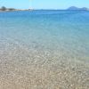 Spiaggia con acque cristalline e barche a vela in lontananza.