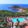 Vista aerea di una piscina vicino al mare, circondata da vegetazione e ombrelloni colorati.