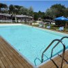 Piscina rettangolare con acqua blu, circondata da una piattaforma in legno e sdraio.
